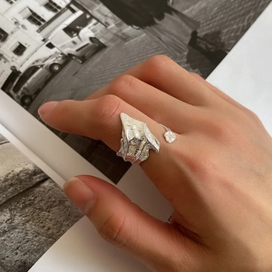 Close-up of irregular textured S925 silver ring with small white stone on finger