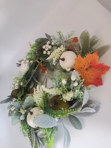 Dettaglio di ghirlanda autunnale con zucche, foglie grigio-verdi e foglia d'acero arancione