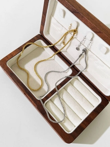 Detail of silver and gold snowflake necklaces resting in a luxury wood jewelry box