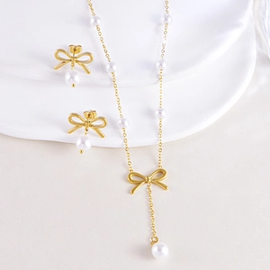 Elegant gold bow necklace and pearl earrings set for women on white display