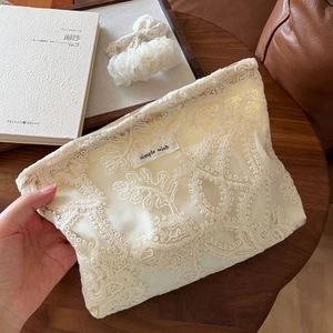 Détails de broderie sur une trousse de toilette en dentelle française avec étiquette