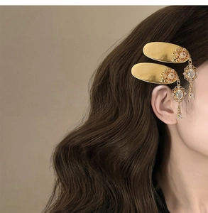 Close-up of golden vintage hair clips with sparkling crystal tassels on model hair