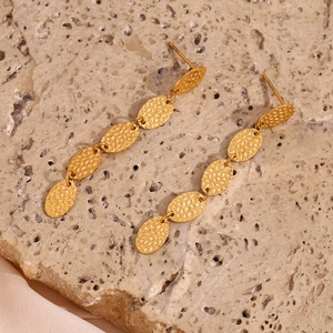 Vue détaillée de boucles d'oreilles longues dorées martelées sur pierre et soie