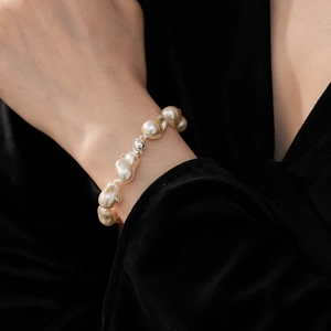 Close-up of irregular baroque pearl bracelet with silver magnetic clasp on a black background