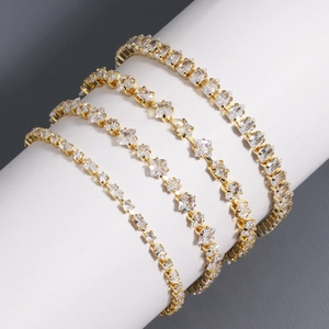 Detail of four gold-plated tennis bracelets with cubic zirconia on a white display