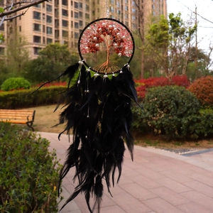 Detail of life tree dream catcher with pink crystal stones and black feathers in a garden
