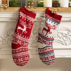 Knitted Christmas stockings with reindeer and snowflake patterns hanging on fireplace
