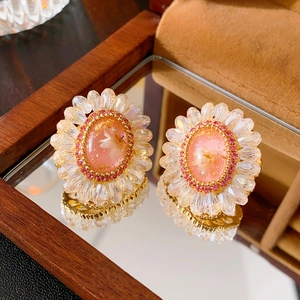 Detail of sunflower earring with pink crystal flower and gold base on a jewelry box