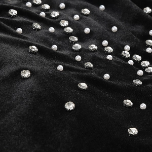 Detail of black velvet evening dress with white pearls and sparkling rhinestone accents