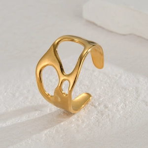 Close-up of golden irregular hollow ring showing wide band and polished metallic texture