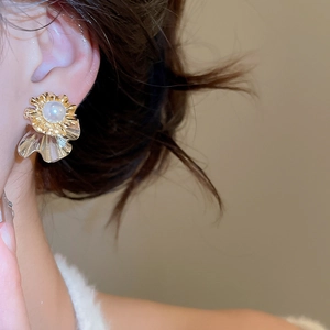 Detailed close-up of vintage golden petal earrings with a lustrous white pearl center