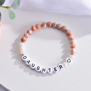 Detail of beaded daughter bracelet with orange natural stones and letter beads