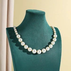 Detail of elegant pearl necklace with gold diamond spacers on green velvet mannequin stand