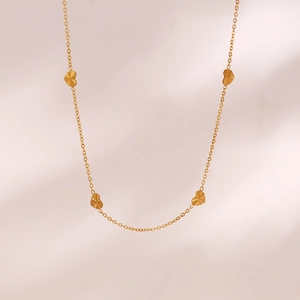 Macro detail of gold-plated stainless steel chain with four heart pendants showing texture