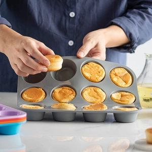 Gray 12-cup silicone muffin pan being used to bake small cakes in a home kitchen
