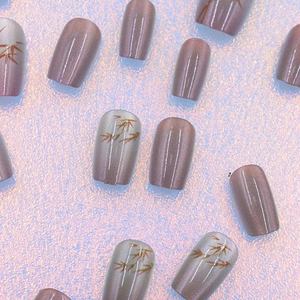 Vue détaillée des faux ongles mauves œil de chat avec motifs de feuilles de bambou peints
