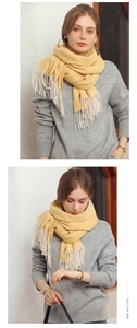 Close-up of yellow herringbone knit scarf featuring delicate cream tassel fringe details