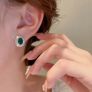 Vintage style oval emerald stud earrings with double halo zircon stones on a model