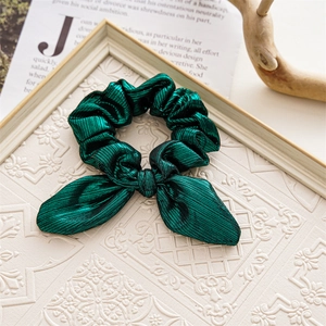Detail of green bow scrunchie on vintage frame and newspaper background