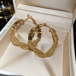 Close-up of golden twisted hoop earrings with geometric blocks in a white jewelry gift box