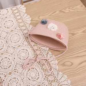 Petit sac en paille rose avec fleurs en tissu sur un chemin de table en dentelle