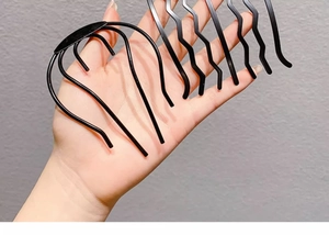 Macro view of black metal U-shaped hair pins and clips held in hand for bun styling