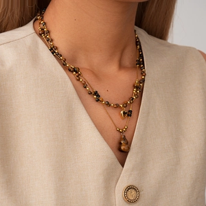 Détail du pendentif gourde en œil de tigre et cœur doré sur un collier porté par un mannequin