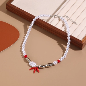 Detail of baroque pearl necklace with red coral pendant and silver accents on jewelry tray