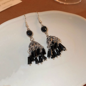 Dettaglio di orecchini vintage a lanterna con nappine in cristallo nero su piatto ceramico