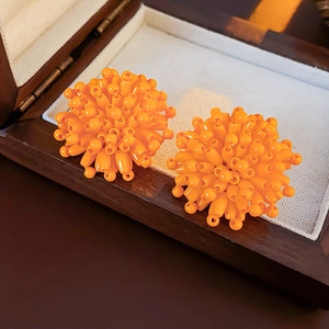 Close-up of bright orange beaded fireworks stud earrings in a wooden jewelry gift box