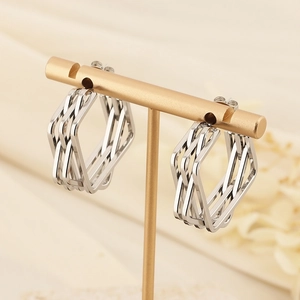 Modern irregular geometric woven silver earrings displayed on a gold metal stand