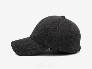 Close-up of deep grey knitted baseball cap with ribbed texture and small metal badge