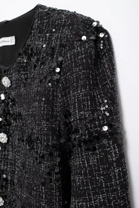 Nahaufnahme der schwarzen Pailletten-Tweedjacke mit gewebter Textur und Strassknopf-Detail