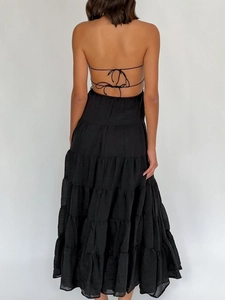 Detail of tiered black halter maxi dress with crisscross tie-back design on professional model