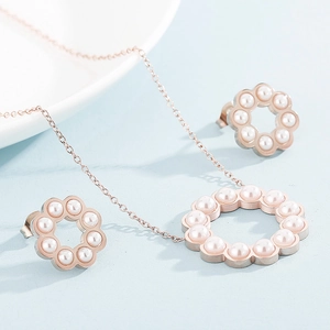 Close-up of rose gold hollow circle jewelry set with inlaid white pearls on light blue background