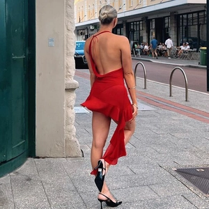 Detail view of backless cowl neck red dress with asymmetrical ruffled hemline