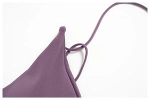 Macro detail of dark purple brushed fabric with fine stitching and slim shoulder straps