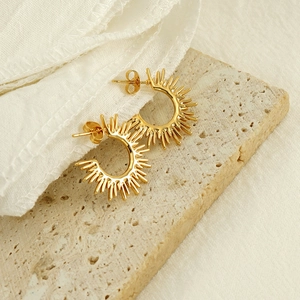 Golden titanium steel C-shape sunburst earrings on minimalist stone background