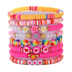 Macro shot of layered Heishi bead bracelets with heart, star, and flower charms