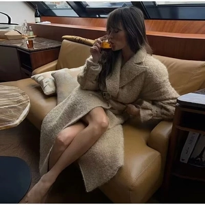 Detailed view of beige faux fur coat featuring double-breasted buttons and metal waist buckle