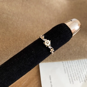 Détail macro d'une bague fleur en nacre plaquée or 14 carats avec zircon sur velours noir