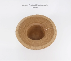 Detail of raffia straw hat interior showing beige adjustable ribbon and frayed brim edges
