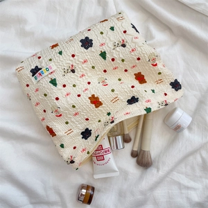 Detail of cotton makeup bag featuring embossed Christmas motifs and colorful brand label