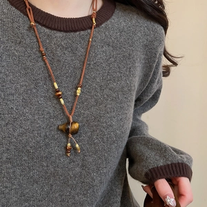 Macro detail of a tiger eye stone gourd pendant on a vintage ethnic long necklace