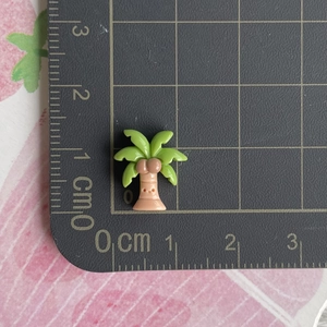 Accessoire palmier miniature en résine avec visage souriant mesuré sur un tapis