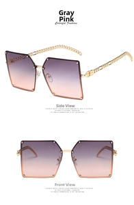 Detail of oversized square sunglasses featuring gradient grey-pink lenses and gold chain temples