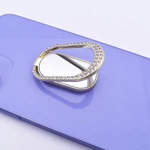 Close-up of golden oval phone ring holder with rhinestones on a purple smartphone