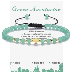 Macro shot of 4mm green aventurine beaded bracelet with gold heart charm on jewelry card