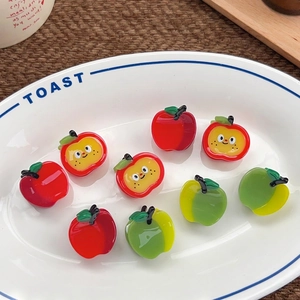 Apple shaped hair claw clips in red and green resin presented on a white plate