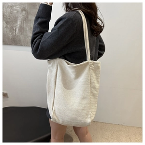 Detail of a large off-white canvas tote bag showing its texture and scale on a model